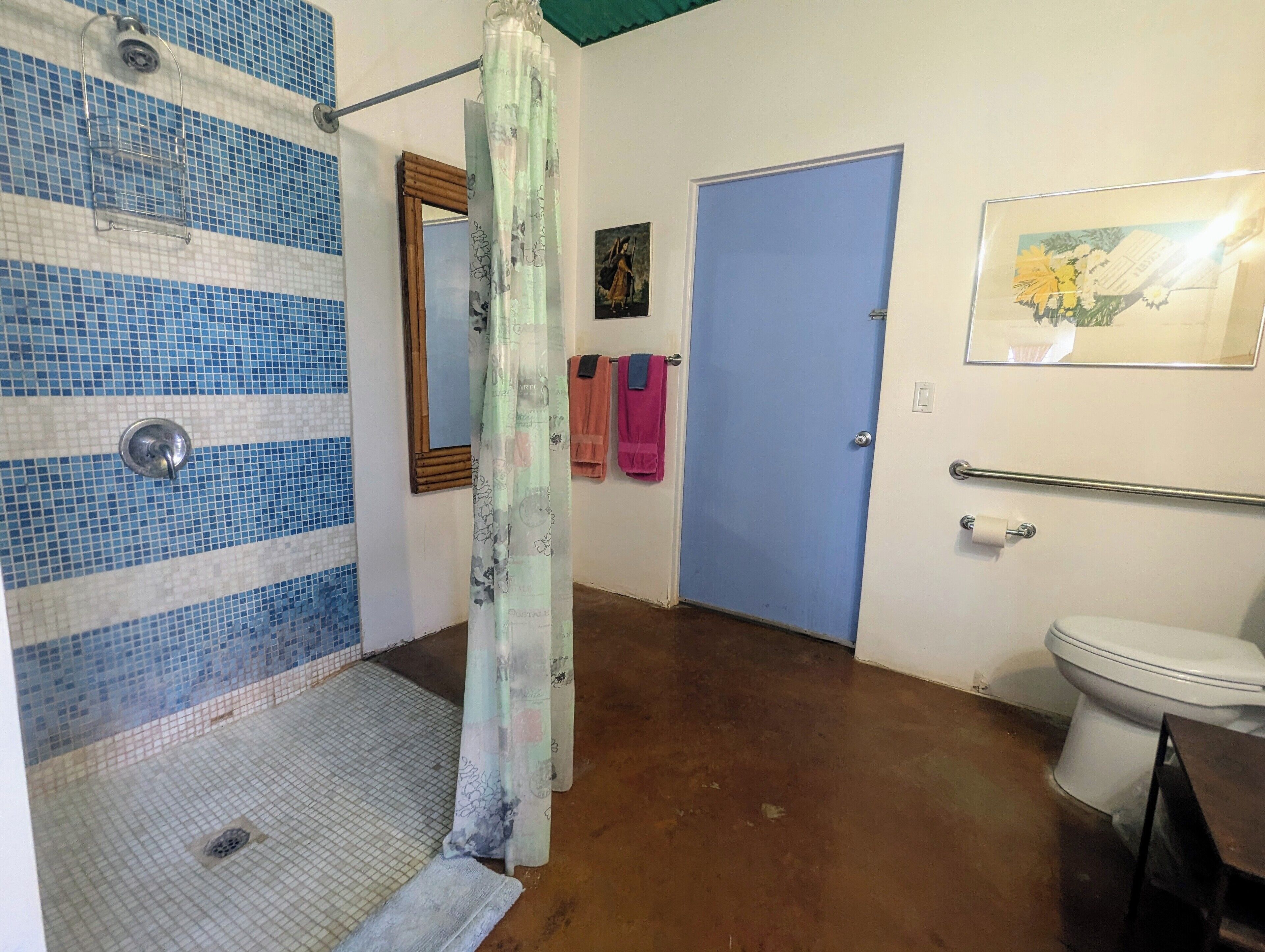 A bathroom with a shower area, a toilet, a sink, and a door.