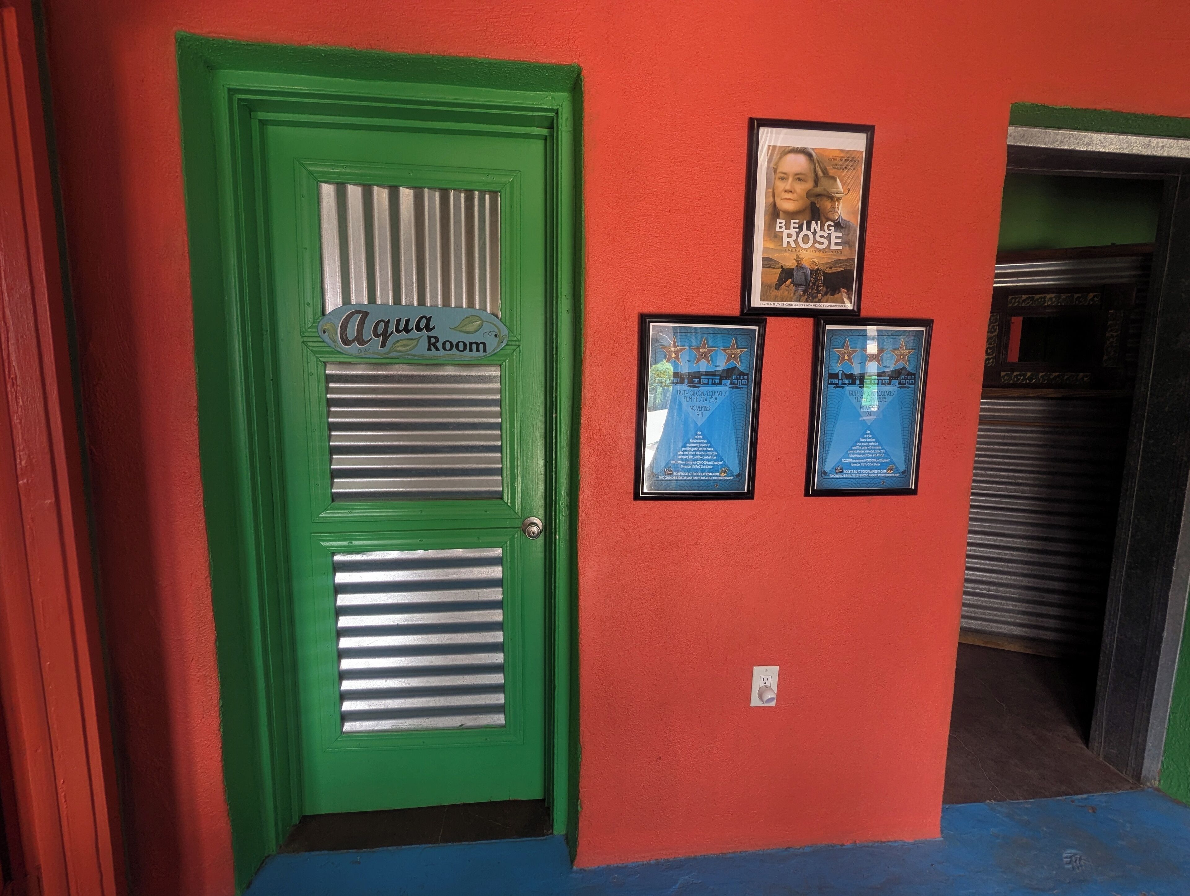 A green door labeled "Aqua Room" with two framed awards on the adjacent wall.