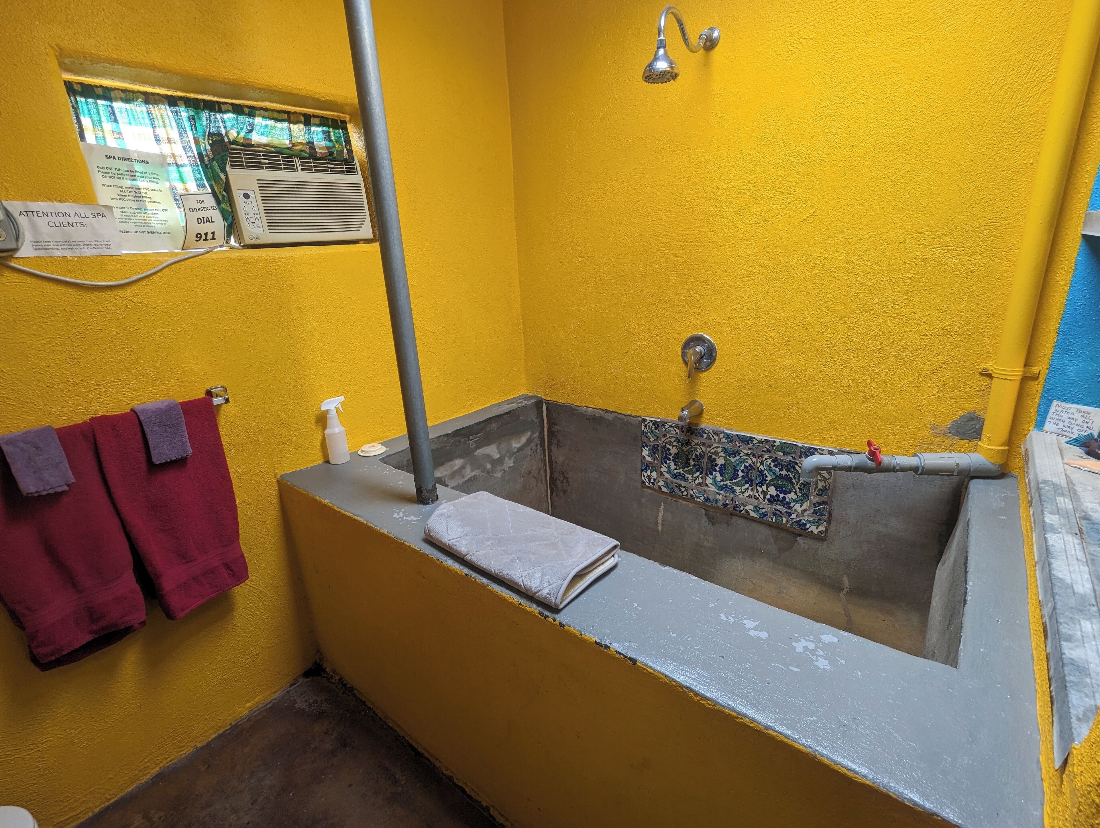 A bathroom with a bathtub, a shower, and a window with a sign.