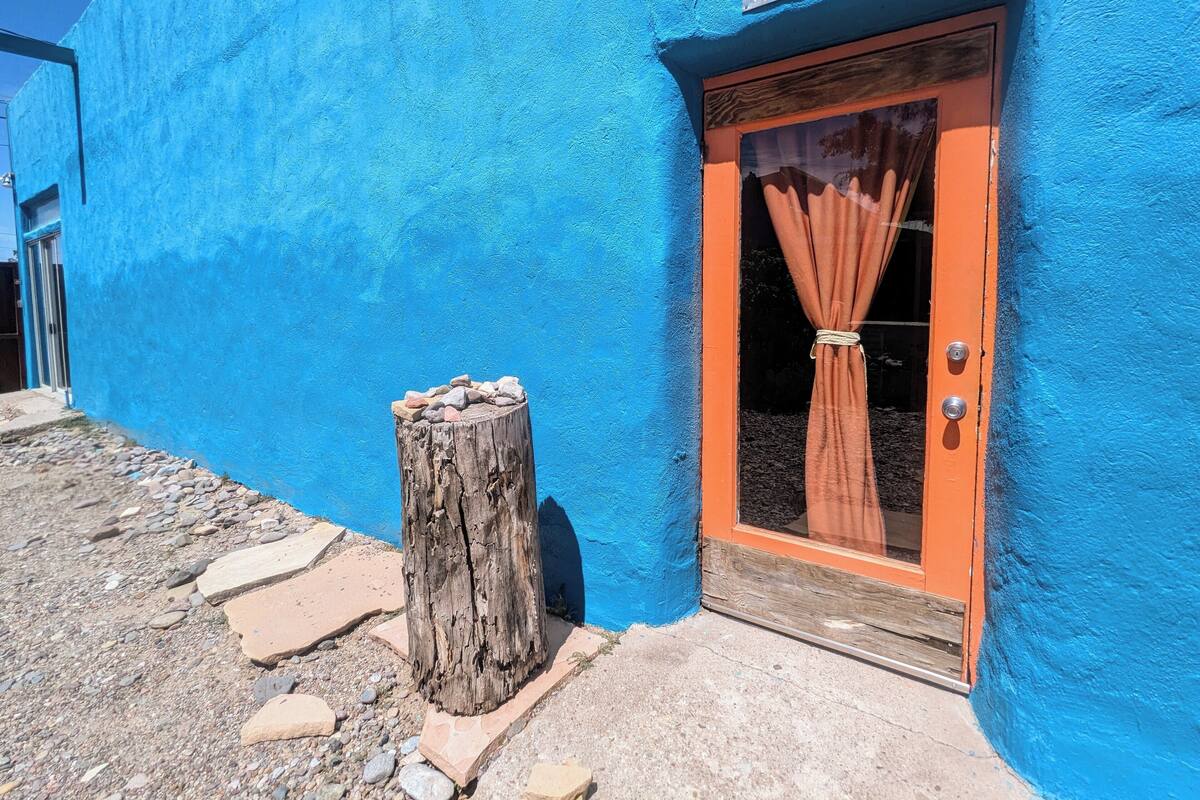 A building with a blue exterior and a wooden door with a curtain.