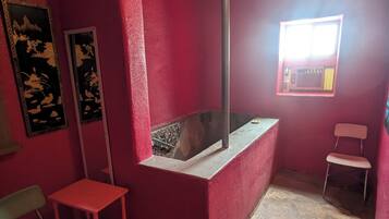 Guest rooms feature a unique ceiling design, a small window with an outside view, and a comfortable seating area.