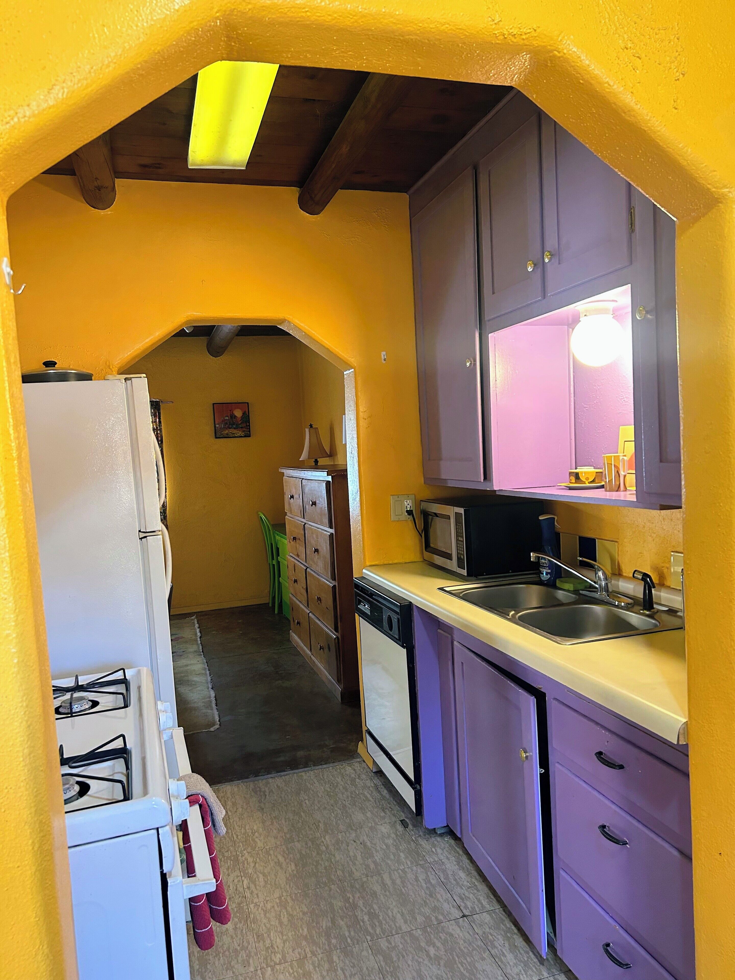 A compact kitchen with a refrigerator, stove, microwave, and sink.