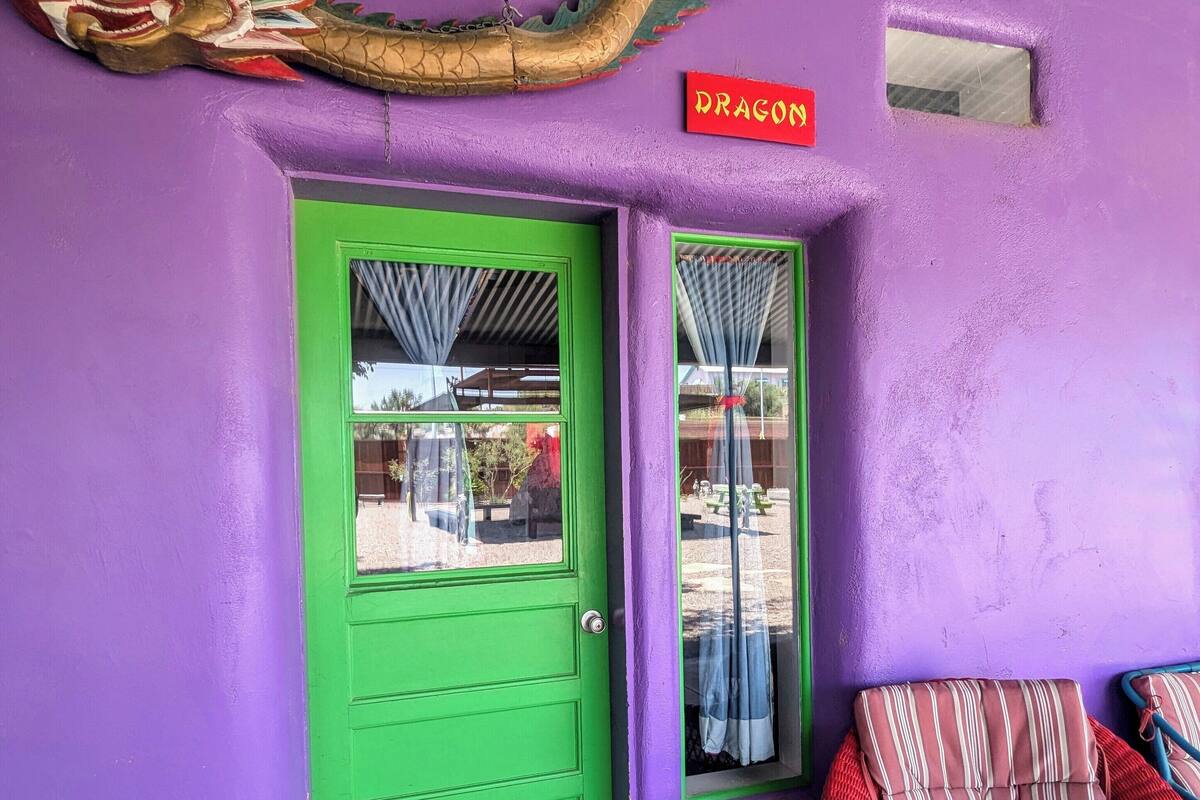 A purple building with a green door, a sign reading "DRAGON", and a red and white striped chair outside.