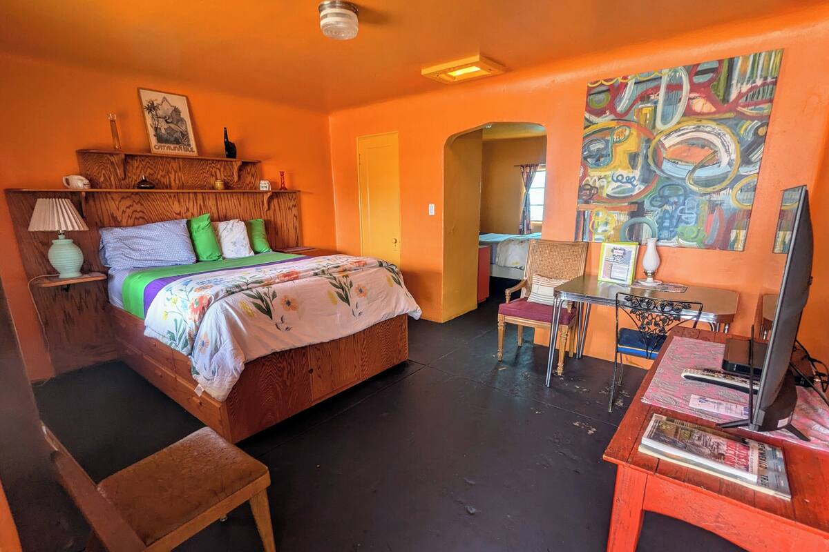 A room with a bed, a desk, a chair, and a television.