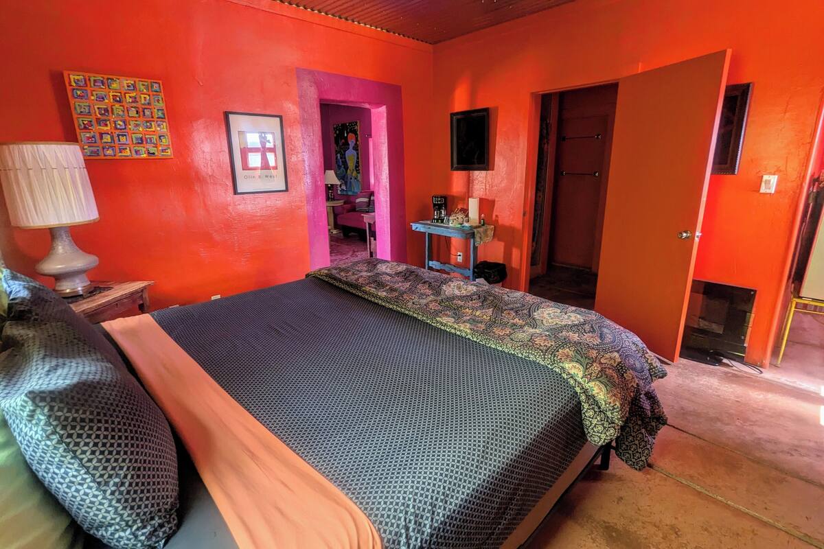 A room with a bed, a desk, a chair, a lamp, and a door.