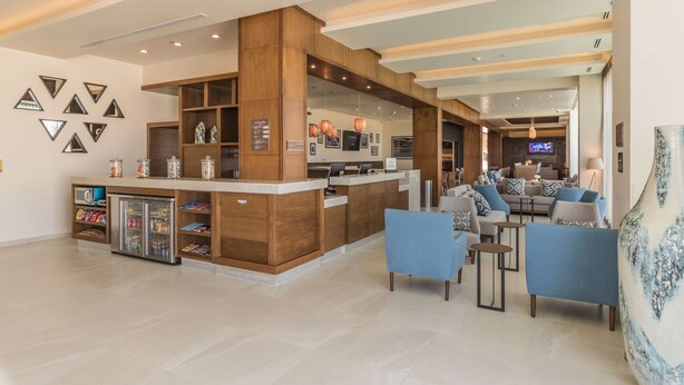 A spacious lobby with a reception desk, seating area, and a refrigerator stocked with beverages. - Hampton Inn & Suites by Hilton Salamanca Bajio (Salamanca)