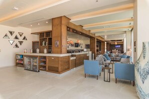 A spacious lobby with a reception desk, seating area, and a refrigerator stocked with beverages. - Hampton Inn & Suites by Hilton Salamanca Bajio (Salamanca)