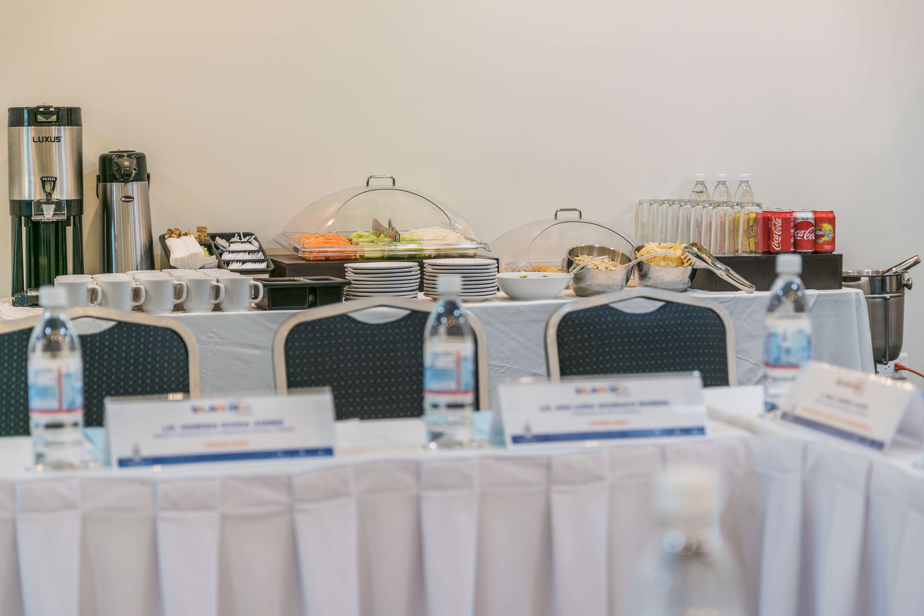 A buffet setup with food, drinks, and coffee machines.