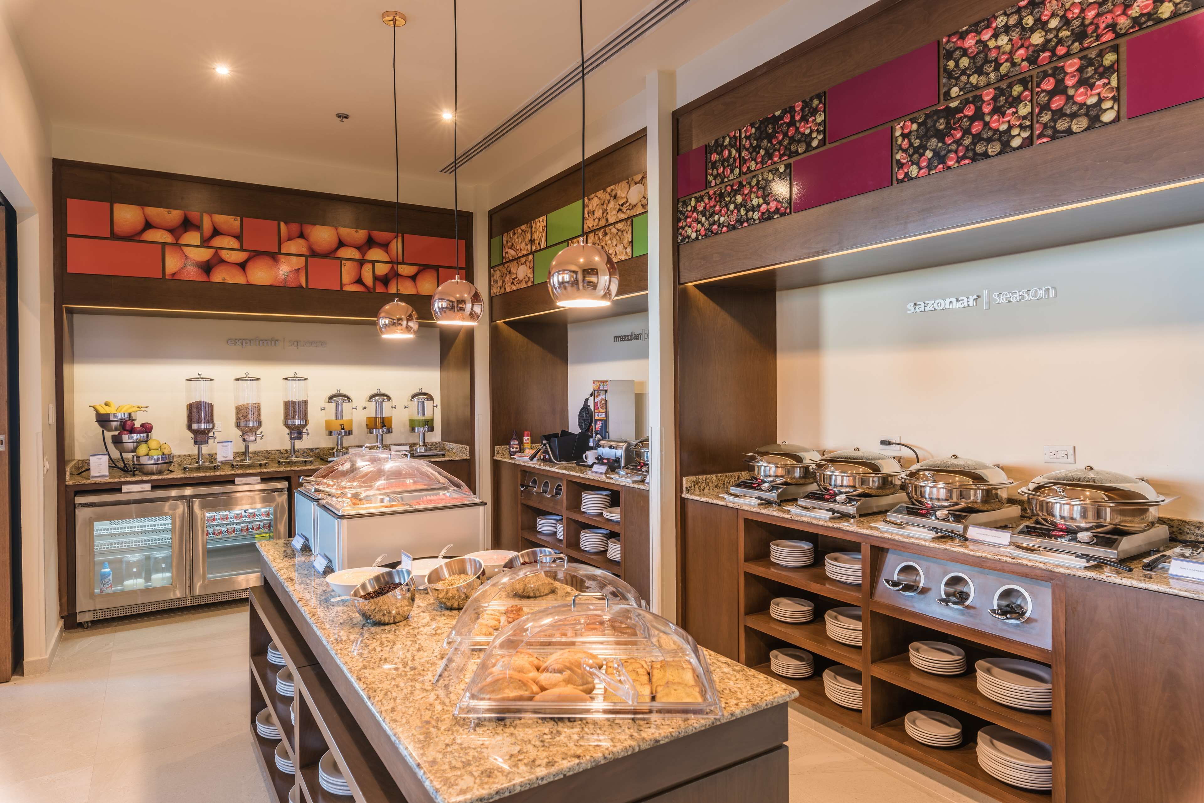 A buffet area with various food stations, including a fruit bowl, coffee dispensers, and a salad bar.