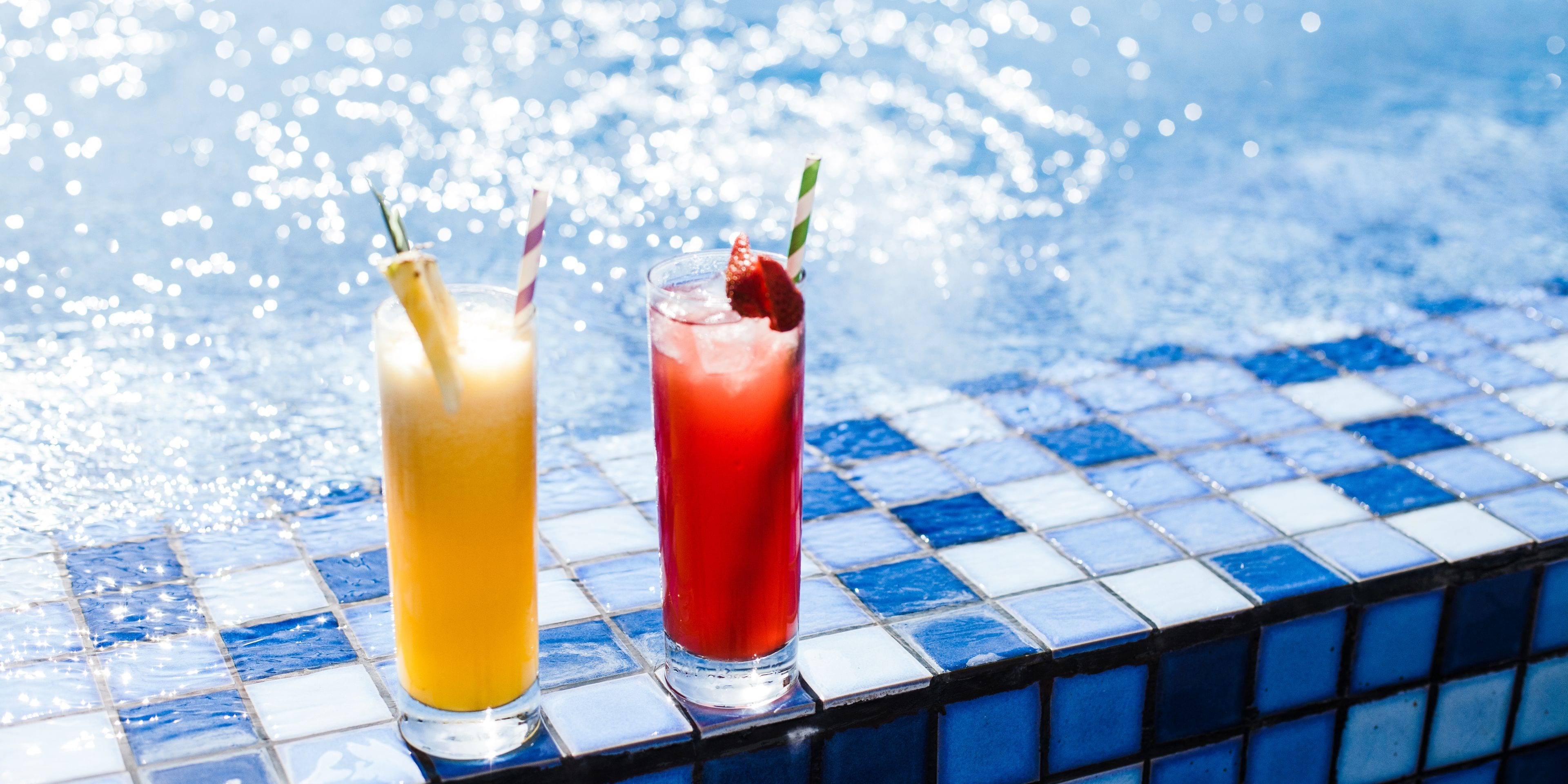 Two drinks on a tiled pool edge.