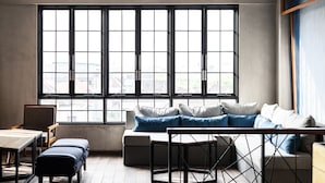 A modern room with a large window, a sofa, a table, and a chair. - Solia Legian Bali (Legian)