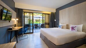 A modern hotel room with a large bed, a desk, a TV, and a balcony with outdoor seating. - Solia Legian Bali (Legian)