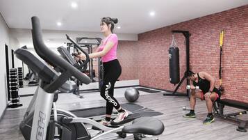 Un gimnasio con cintas de correr, un saco de boxeo y equipo de levantamiento de pesas.