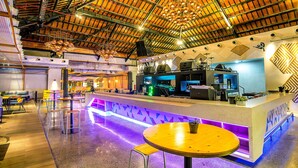 A modern bar area with a high ceiling, bar stools, and a neon-lit counter. - Solia Legian Bali (Legian)