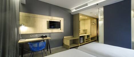 Une chambre d’hôtel moderne équipée d’un lit, d’un bureau, d’une chaise, d’une télévision et d’une armoire intégrée.