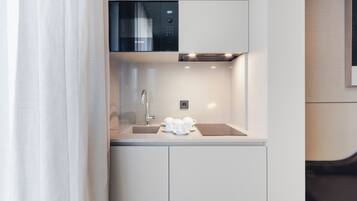 A compact kitchen with a Bosch microwave, a sink, and a coffee station.