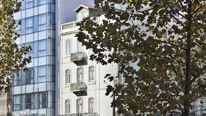 Een hotel met een moderne glazen gevel, een zichtbaar balkon en een bordje met de tekst 'Hotel White Lisboa'.