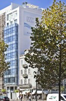 A hotel with a modern glass facade, a visible balcony, and a sign for 'Hotel White Lisboa'.