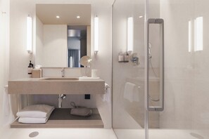 Une salle de bain moderne avec une douche à parois de verre, un lavabo avec un miroir et un porte-serviettes.