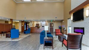 A spacious lobby with a reception desk, blue and red seating, a flat-screen TV, and a fireplace. - Comfort Suites Billings (Billings)