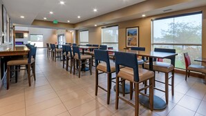 A spacious dining area with multiple tables and chairs, large windows with a view, and a modern interior design. - Comfort Suites Billings (Billings)