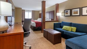 A hotel room with a desk, chair, blue sofa, and a bed with a red blanket. - Comfort Suites Billings (Billings)