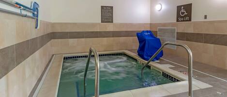 A spa pool with metal railings, a blue towel, and a sign indicating a spa lift.