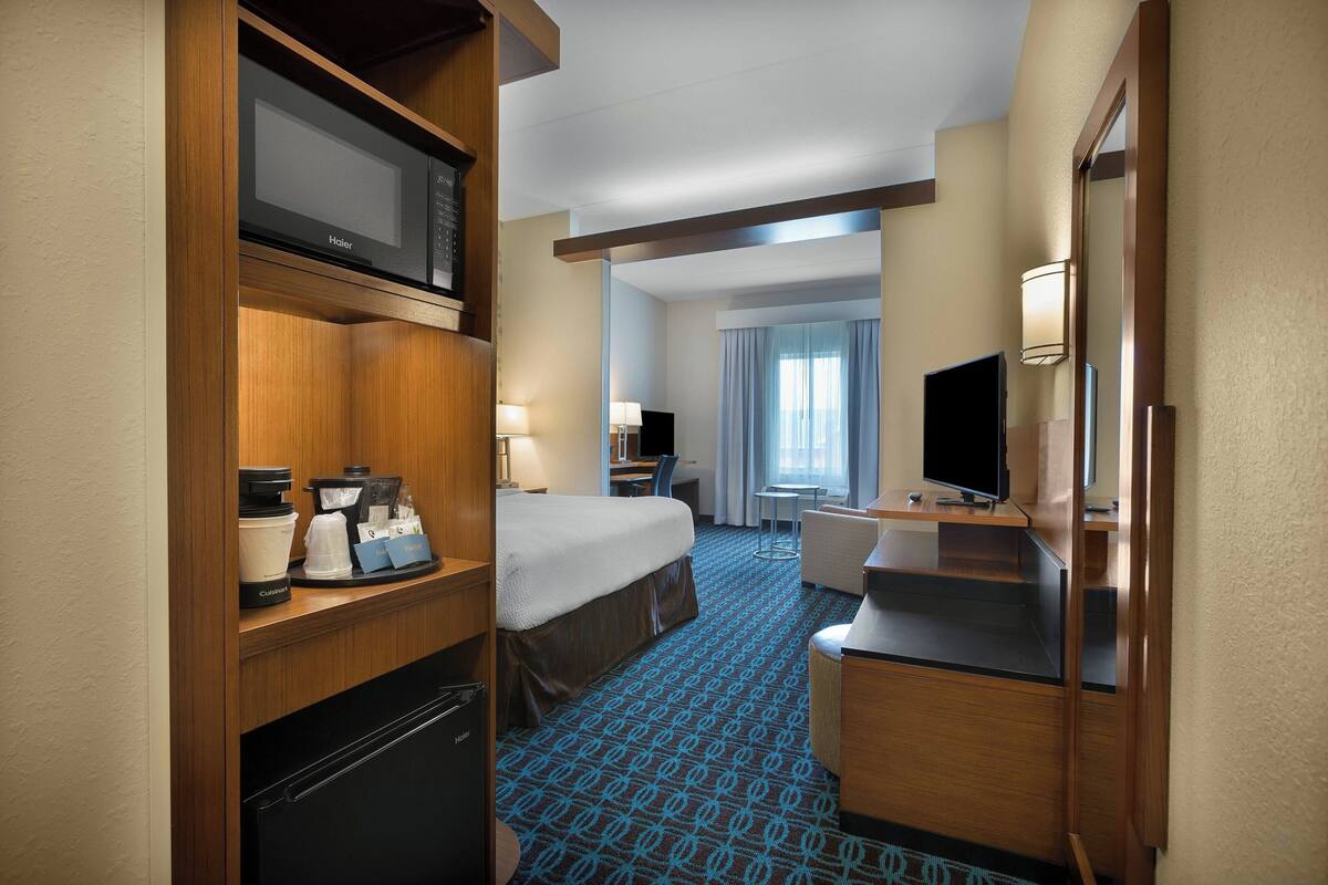 Hotelkamer met een bed, bureau, magnetron, koffiezetapparaat, televisie en een badkamer.