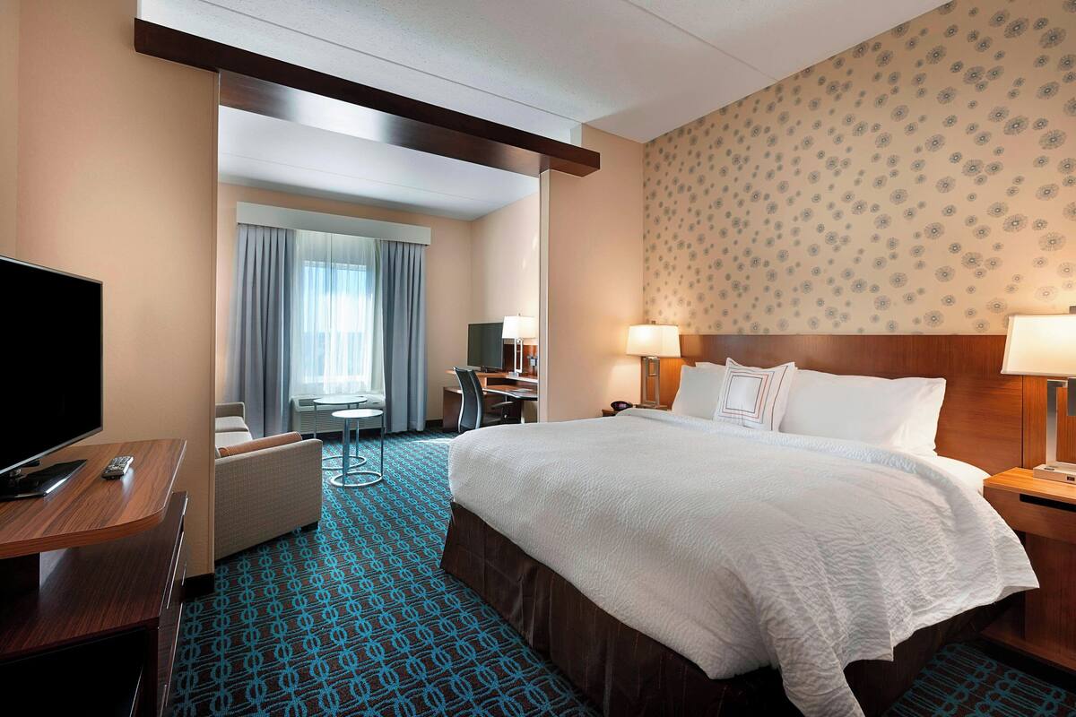 Een hotelkamer met een groot bed, een bureau, een televisie en een zithoek.