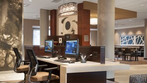 A modern hotel reception area with a reception desk, multiple computer monitors, and comfortable seating.