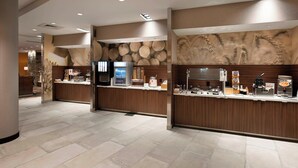 A modern hotel lobby with a reception desk, a coffee machine, and a wall with a circular pattern.