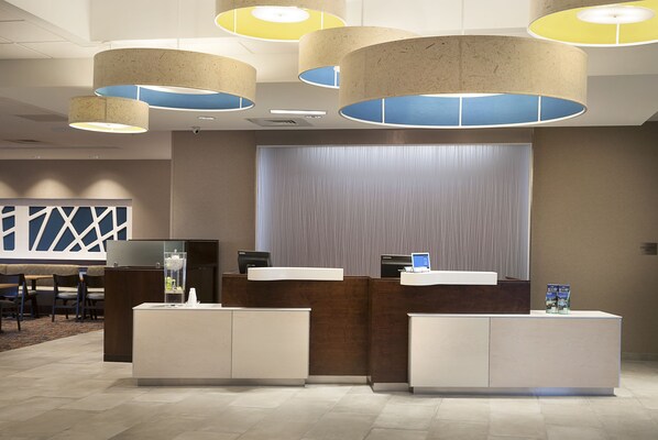 Un área de recepción con diseño moderno, que incluye un mostrador de recepción, una zona de estar y un ventanal grande.