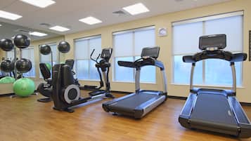 Een sportschool met loopbanden, elliptische trainers en fitnessballen.