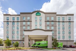 Un hotel a più piani con un furgone verde parcheggiato davanti.
