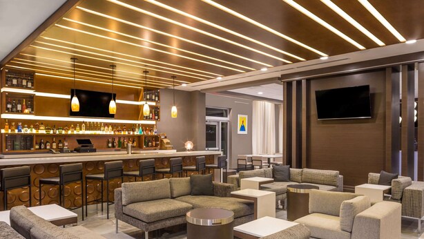 Zona de bar moderna con asientos y una pantalla de televisión.