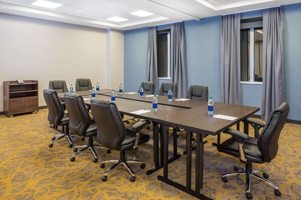 A conference room with a long table, eight chairs, and water bottles. - Wingate By Wyndham Miami Airport (Miami)