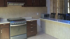 A kitchen with a stove, cabinets, a microwave, and a chandelier. - Casa de la Montaña (San Miguel de Allende)
