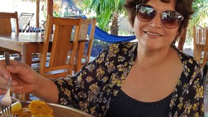 A person seated at a wooden table with a plate of grilled fish and chips. - Hotel Popoyo (Tola)