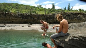 A natural pool with clear water, surrounded by rocky terrain and sparse vegetation. - Hotel Popoyo (Tola)