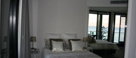Une chambre à coucher avec un lit, des tables de chevet et une vue sur la mer.