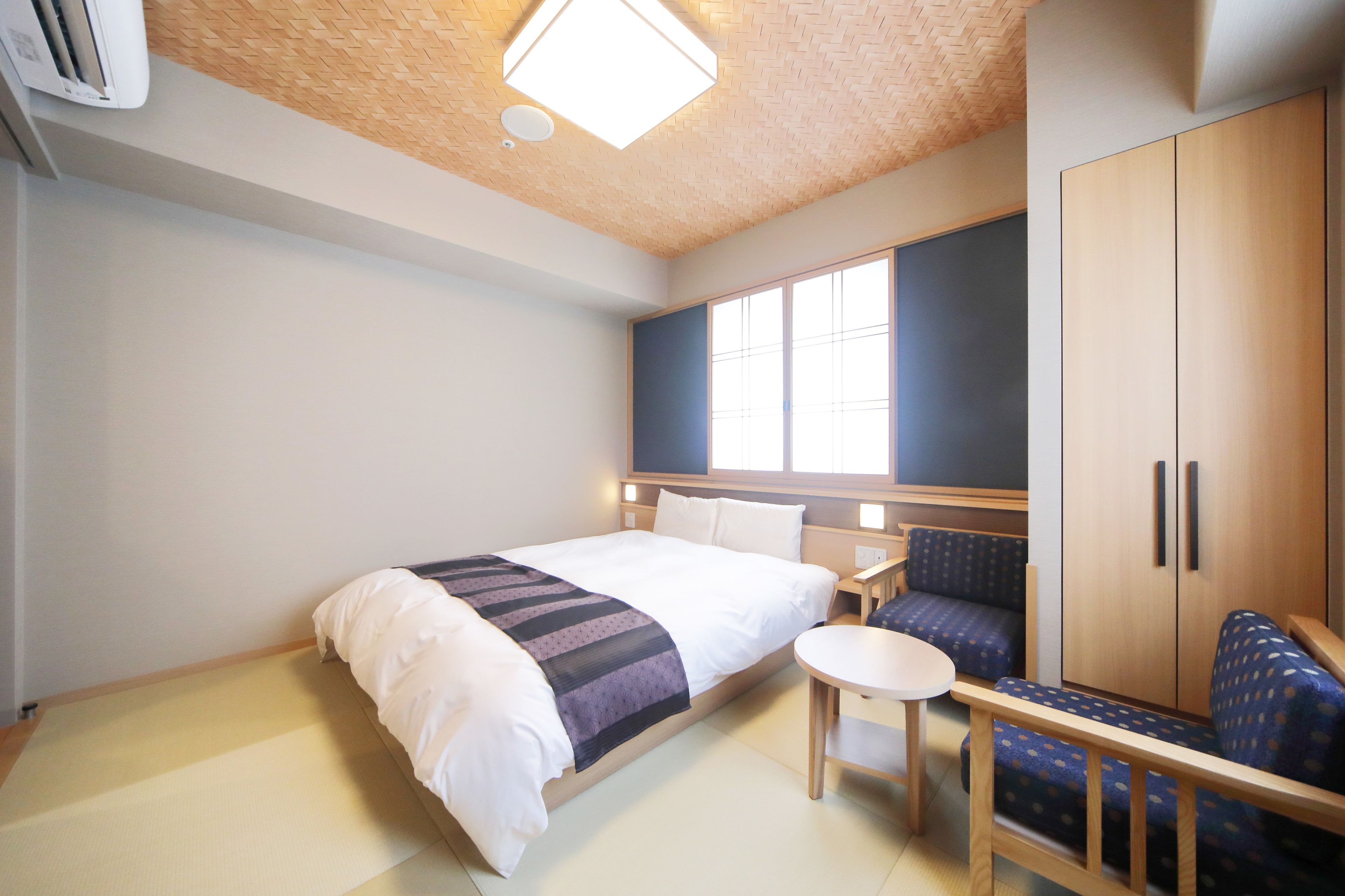 A hotel room with a bed, a small table, a sofa, and a wardrobe.