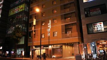 A multi-story building with illuminated signage, a bicycle parking area, and a storefront with a sign in a foreign language.