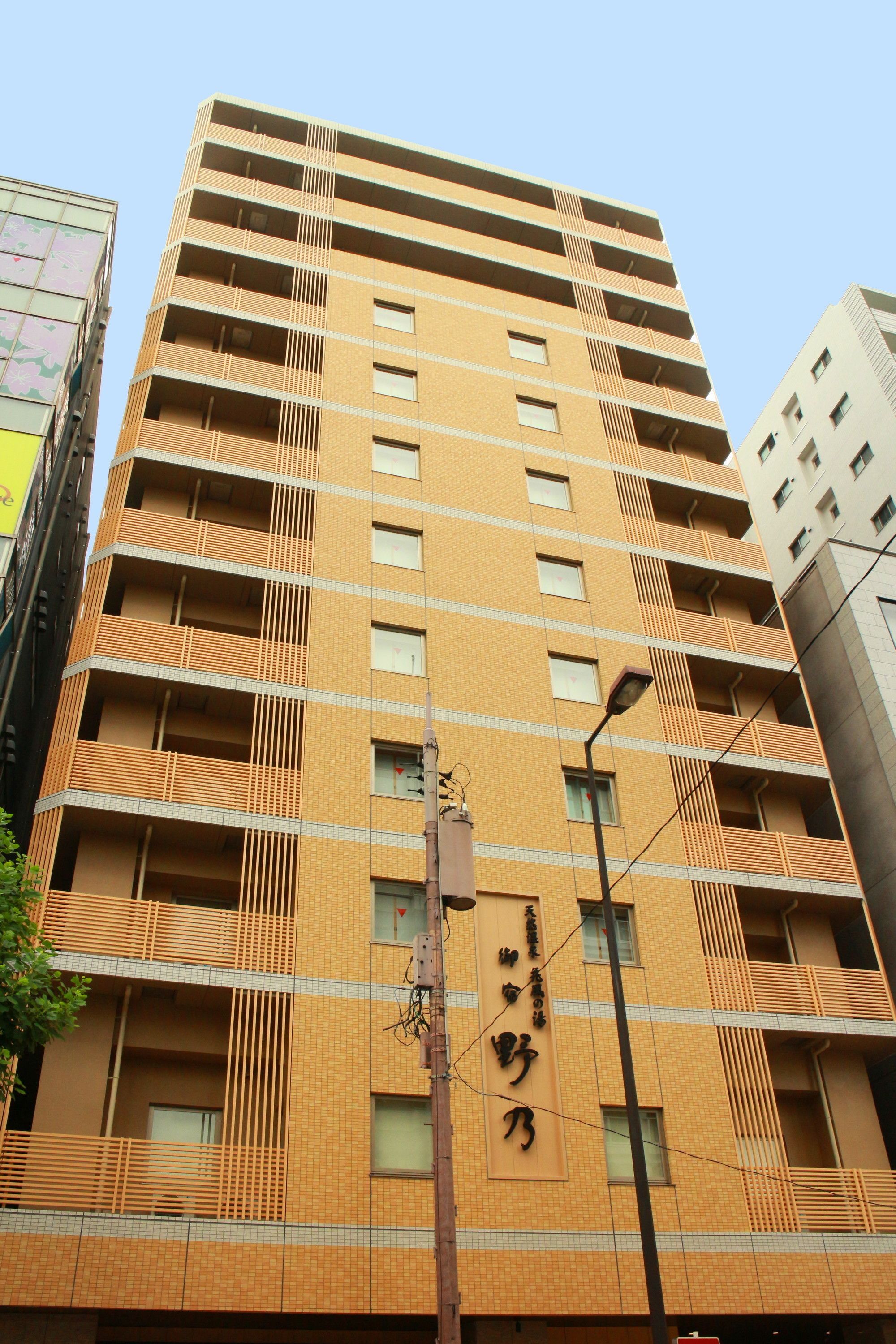 A multi-story building with a beige facade, multiple balconies, and a visible sign with Chinese characters.