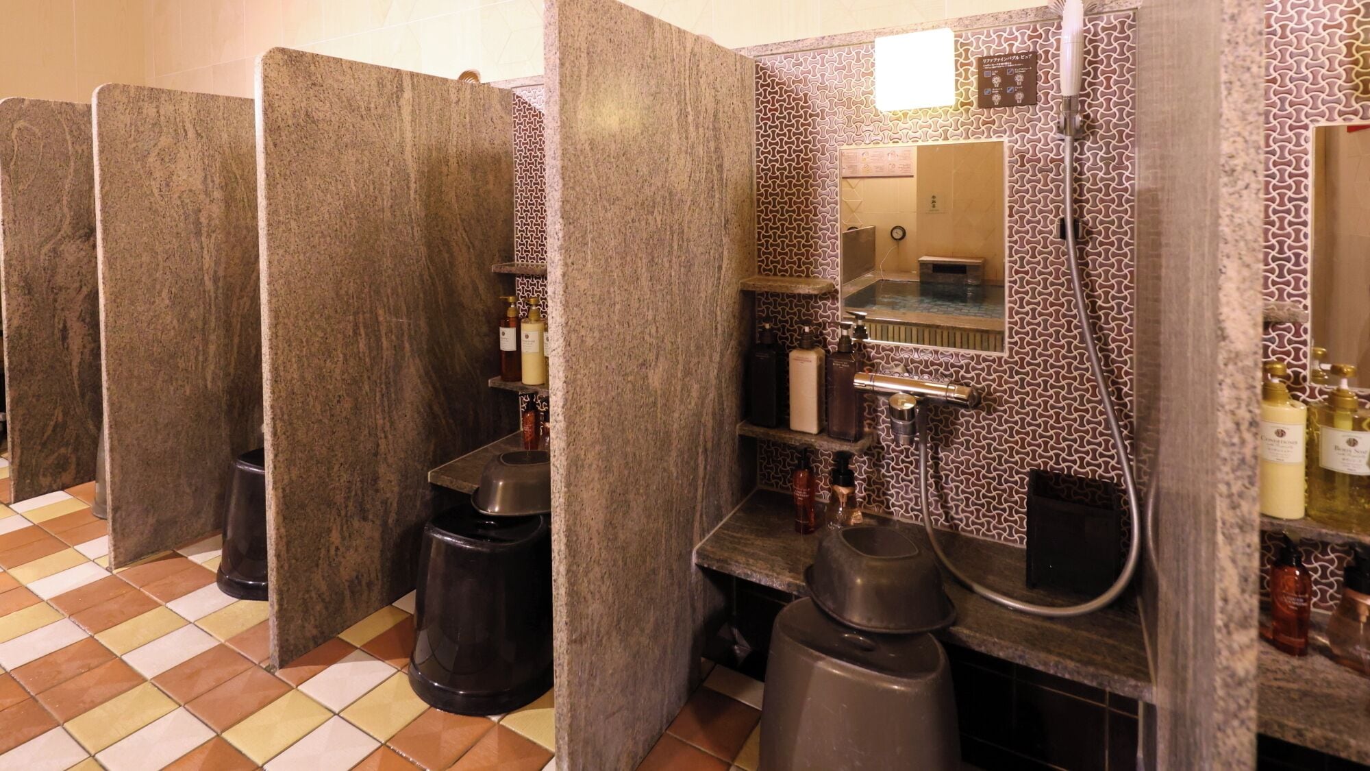 A public restroom with individual stalls, a sink, and a mirror.
