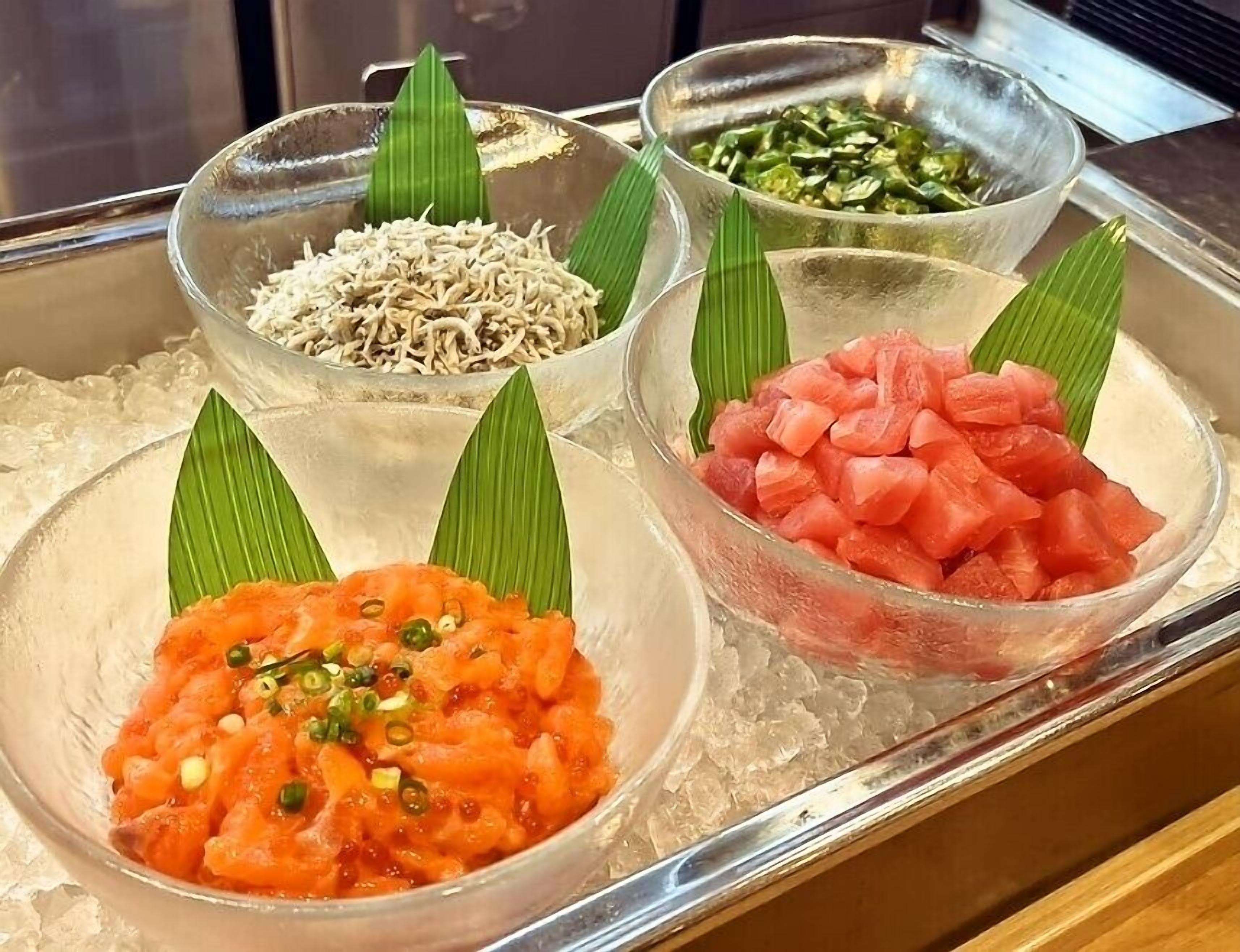 A tray with four bowls of food on ice, each garnished with a green leaf.