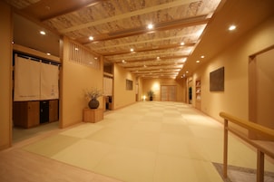 A spacious hallway with a checkered floor, wooden lockers, and a potted plant.