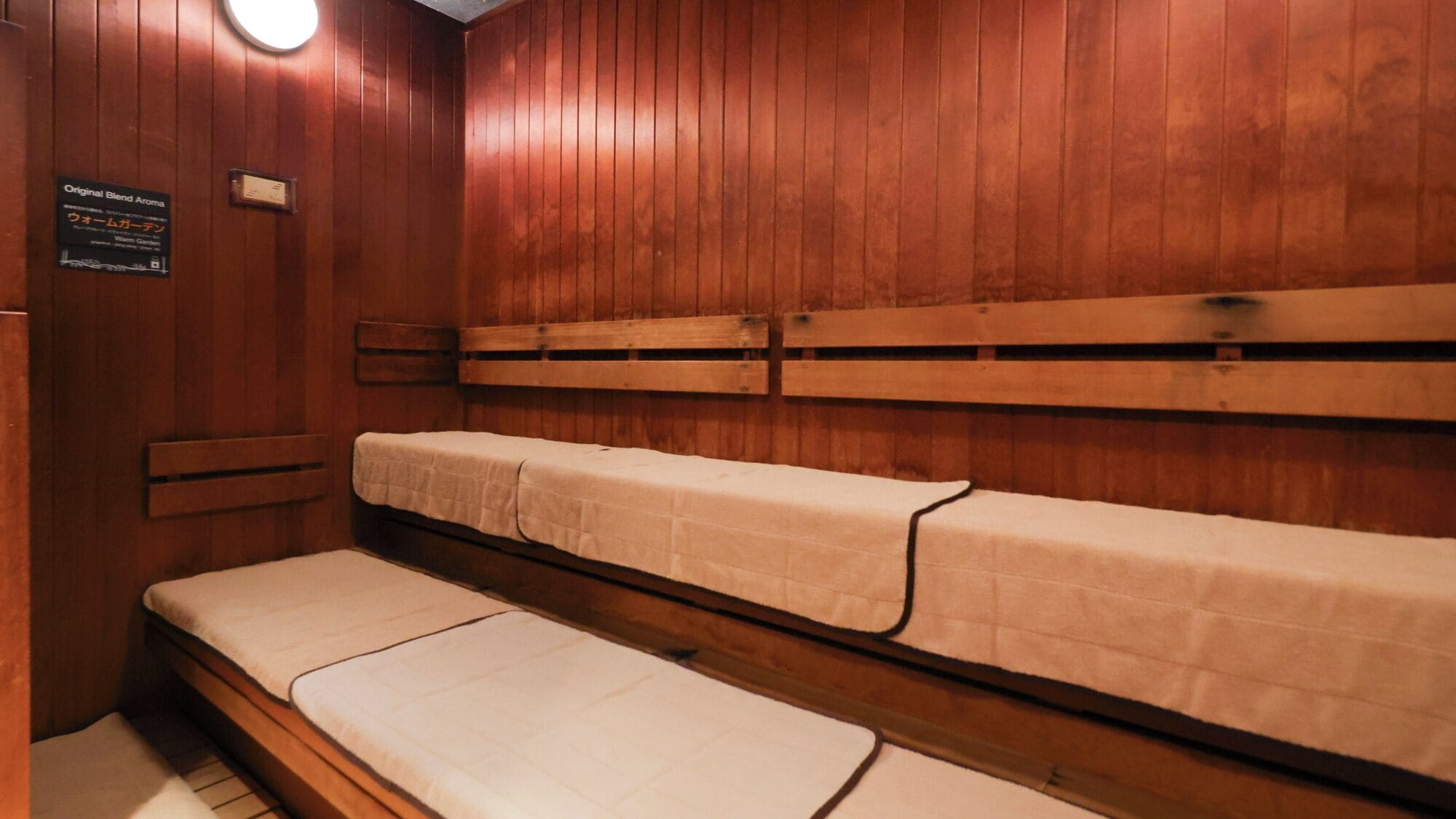 Un sauna avec des bancs en bois et des coussins recouverts de serviettes blanches.
