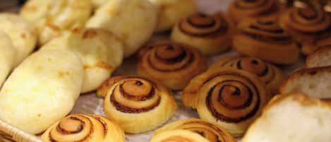 A variety of baked goods, including cinnamon rolls and other pastries, displayed in a basket.