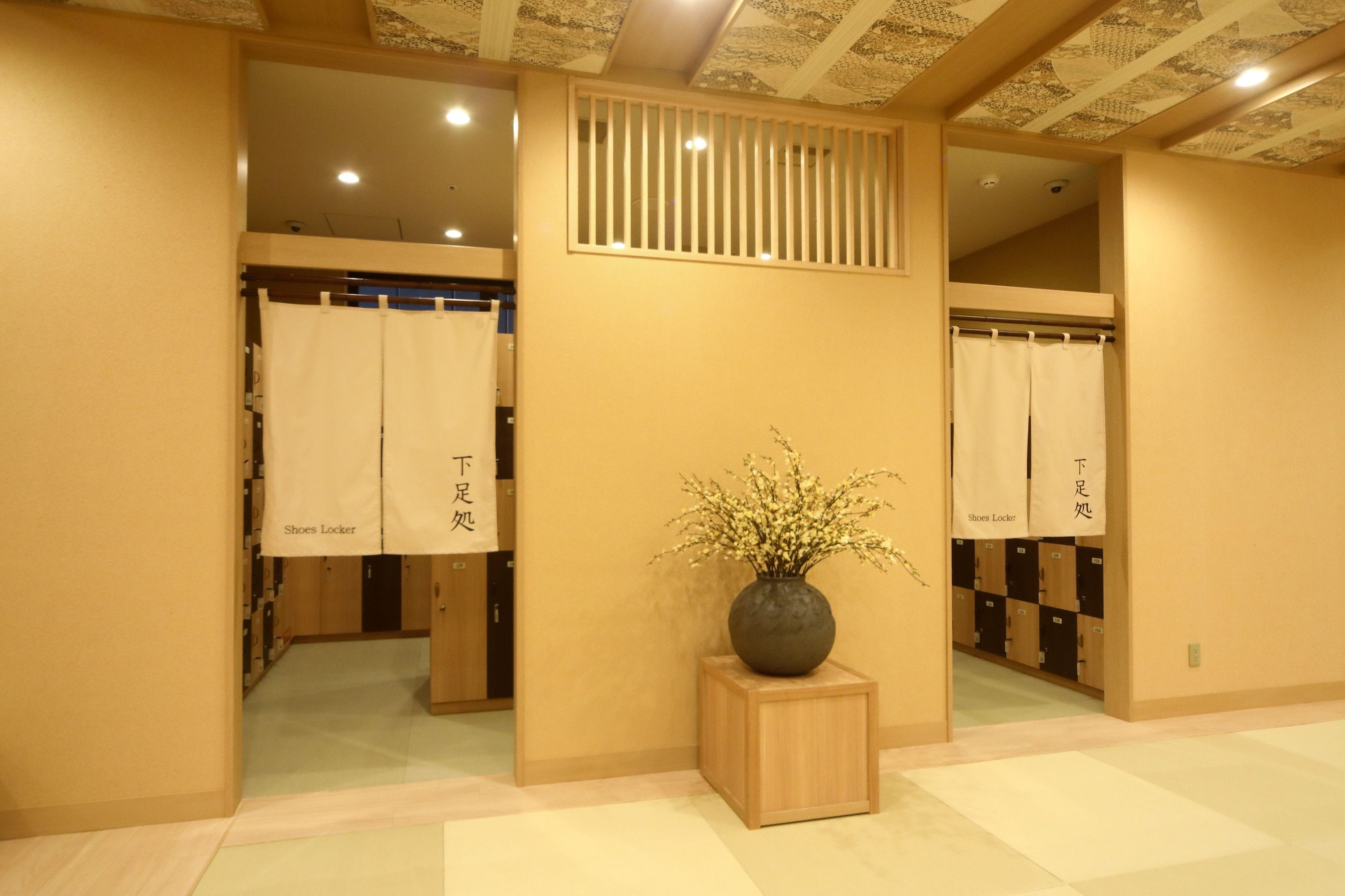 A hallway with shoe lockers and a vase with flowers.