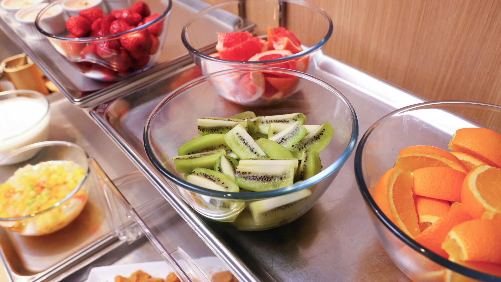 A buffet with various fruits including kiwi, strawberries, and oranges.